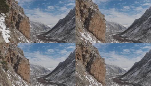 这是初春大雪纷飞的山峡岩石旁的跨度的鸟瞰图。高清在线视频素材下载