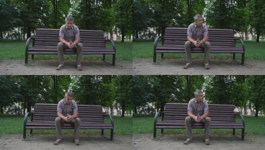 一名男子坐在城市公园的长椅上看手表高清在线视频素材下载