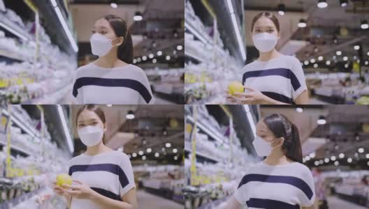 亚洲女性家庭主妇拉着手推车在商场超市挑选商品，女性戴着口罩在商场商店里行走寻找消费品高清在线视频素材下载
