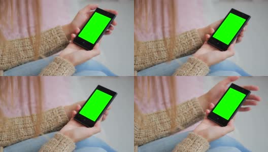 一个女人在看绿色屏幕的智能手机高清在线视频素材下载