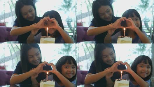 女孩和妈妈一起享用着生日蛋糕，手打心牌高清在线视频素材下载