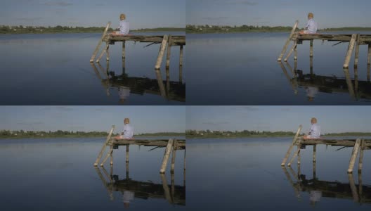 牛郎坐在码头上，在湖里捕鱼高清在线视频素材下载