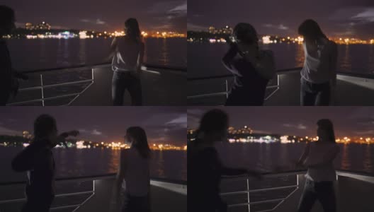 夜晚，两个美丽的年轻女子在甲板上跳舞的剪影。船上的闺蜜高清在线视频素材下载