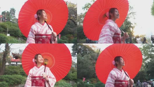 微笑的年轻美丽的亚洲女性游客穿着粉红色的传统日本和服拿着红色的伞放松和享受旅游假期在东京城市的公共公园，日本高清在线视频素材下载