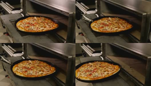 厨师在一家餐厅烤披萨，他把披萨从烤箱里拿出来。高清在线视频素材下载