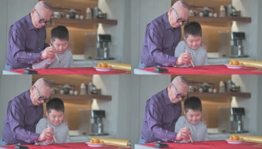 亚洲华人小男孩向他的祖父学习写中国书法高清在线视频素材下载