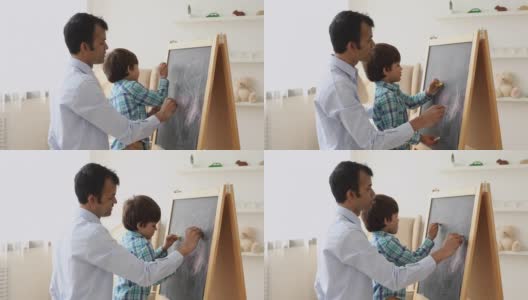 印度父亲和儿子一起用粉笔在黑板上画画高清在线视频素材下载