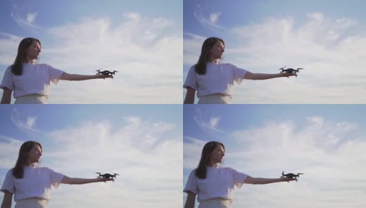 这名女孩是一名无人机驾驶员，在日落时分手里拿着一架正在工作的无人机。女性手中的小型四轴飞行器的螺旋桨正在工作高清在线视频素材下载