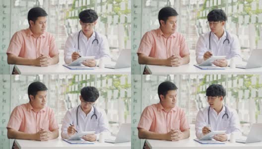 亚洲医生在诊所边用药片边和病人交谈，解释病人的病情和治疗结果。高清在线视频素材下载