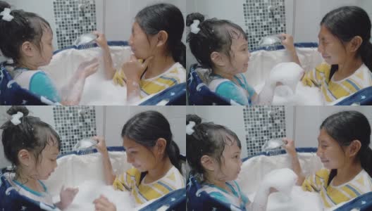 快乐的亚洲孩子们在塑料浴缸里对着姐姐的脸吹泡泡，一起大笑，生活理念。高清在线视频素材下载
