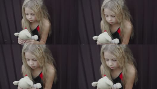 一个不整洁的女孩脸上的表情，手里拿着一个简单的玩具。蓬乱的头发和孩子的悲伤表情。高清在线视频素材下载