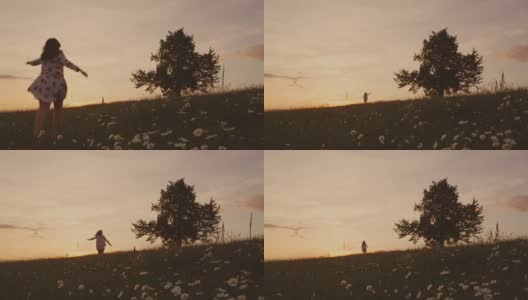 无忧无虑的女孩奔跑在田园诗般的日落夏令草地上，朝着树，实时。春天。高清在线视频素材下载