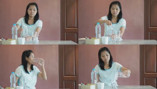 亚洲妇女把水从瓶子倒到玻璃杯里然后喝。高清在线视频素材下载