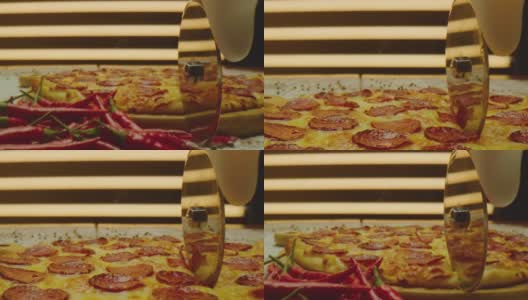用圆刀切披萨。美味的披萨被切成块的特写镜头。烤披萨配香肠，芝士，红辣椒。ARRI ALEXA用老瓦镜头拍摄。相机移动高清在线视频素材下载