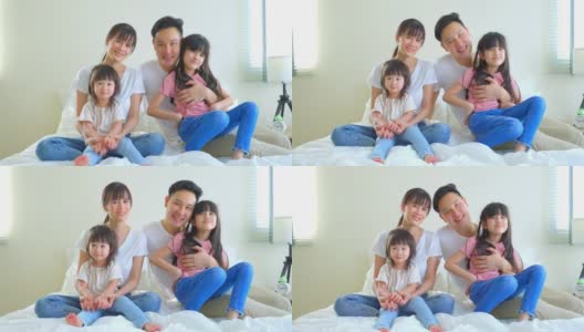 亚洲幸福家庭的肖像微笑和看相机在家里的床上。爱的夫妇和年幼的小女孩兄弟姐妹的女儿喜欢早上在卧室一起活动后从家里醒来。高清在线视频素材下载
