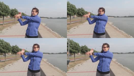 年轻美丽快乐的运动健身女人站在河边伸展她的肌肉准备慢跑和跑步锻炼，同时她集中精力锻炼和训练动机高清在线视频素材下载