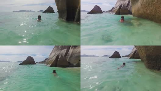 一个小男孩(7岁)在塞舌尔安斯源德阿金特海滩的岩石中游泳高清在线视频素材下载