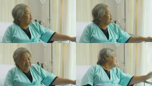 老年妇女坐在病床上和躺在医院里，悲伤的残疾人在病床上感到孤独。退休妇女独自在诊所里。高清在线视频素材下载
