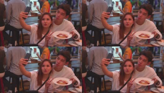 一对年轻情侣在餐厅用手机自拍高清在线视频素材下载