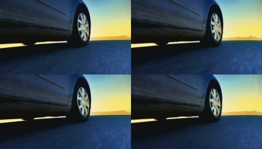跑车行驶在狭窄的道路朝着阳光在日落，低角度的观点高清在线视频素材下载