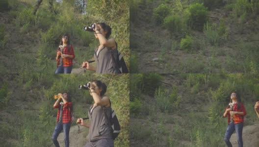 年轻女性在山林中徒步旅行时使用双筒望远镜。高清在线视频素材下载