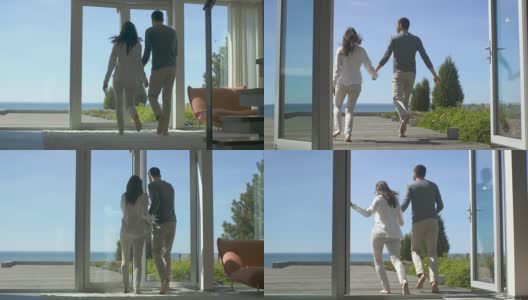 下面的镜头是一对美丽的夫妇打开阳台门，走到阳光明媚的阳台上，有海边的景色。天空万里无云，人们快乐。高清在线视频素材下载