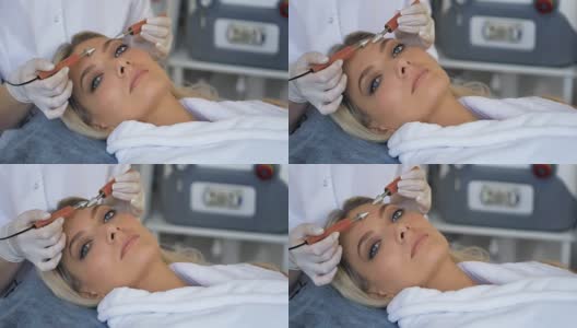 美丽的女人接受面部微电流治疗的特写从治疗师在比美沙龙高清在线视频素材下载