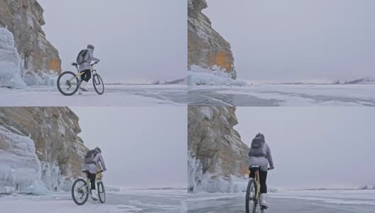 一个女人在冰洞附近骑自行车。有冰洞和冰柱的岩石非常漂亮。这个女孩穿着银色的羽绒服，背着自行车背包，戴着头盔。旅行者正在骑自行车。高清在线视频素材下载