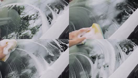 男人的手用海绵和泡沫擦洗汽车的挡风玻璃。汽车服务理念，高清在线视频素材下载