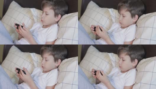 7岁小孩躺在床上玩小玩意高清在线视频素材下载