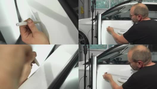 汽车修理店左车门表面凹痕修复视频流程。技术员正在使用工具进行无漆凹痕修复。高清在线视频素材下载