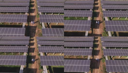 工程师和技术员在太阳能电池板的阴影下检查太阳能电池板农场，电力，太阳能产生的清洁能源的鸟瞰图高清在线视频素材下载