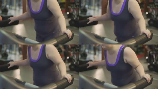 不健康的超重妇女因在跑步机上锻炼，行走缓慢而疲惫不堪高清在线视频素材下载