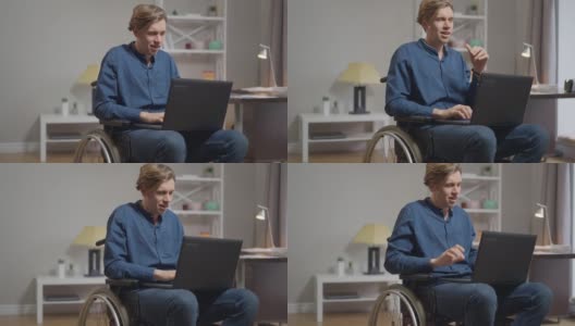 一名自信而专注的年轻残疾男子在笔记本电脑键盘上发短信，看着相机微笑。满意快乐的白人自由职业者在轮椅摆姿势在家里的慢动作。高清在线视频素材下载