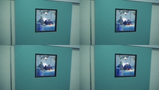 医生和护士做手术。透过窗户可以看到医院的手术过程。大流行期间的手术室。冠状病毒高清在线视频素材下载