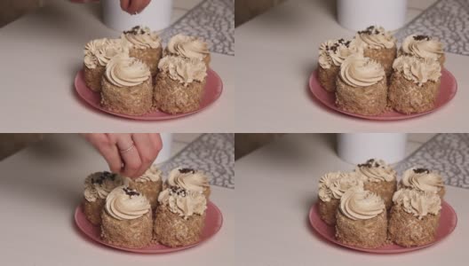 一位女士用奶油和饼干屑做海绵蛋糕。用奶油和巧克力末装饰。特写镜头。高清在线视频素材下载