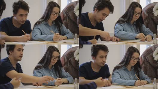 专注的年轻女子戴着眼镜和年轻男子学习绘画课程高清在线视频素材下载