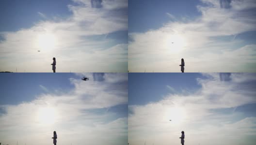 一位专业的无人机驾驶员在日落的天空下控制着它。直升飞机运营商轮廓高清在线视频素材下载