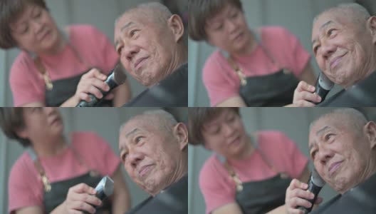 一名亚洲华人女子在白天坐在轮椅上为父亲理发高清在线视频素材下载