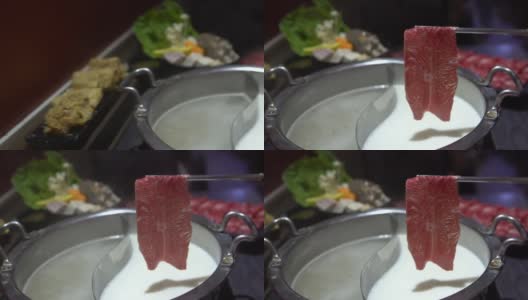 生牛肉用筷子夹住。中国的铜锅火锅高清在线视频素材下载
