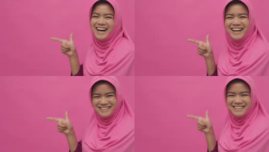 SLO MO穆斯林妇女的肖像与手势指向你的标志粉红色的背景拷贝空间高清在线视频素材下载