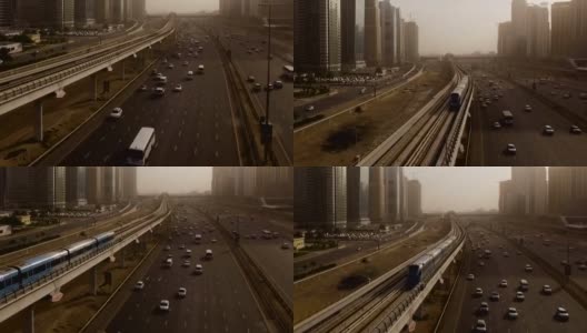 从空中俯瞰蓝色的高速列车，它穿过高速公路上的立交桥，汽车被摩天大楼包围。迪拜,阿联酋高清在线视频素材下载