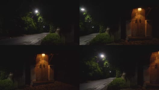 在一个宁静的夜晚，路边有一扇带灯的复古门。晚上全景高清在线视频素材下载