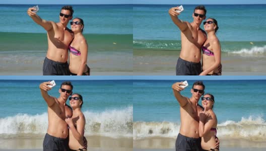微笑的一家人在蔚蓝海洋附近的阳光沙滩上自拍高清在线视频素材下载