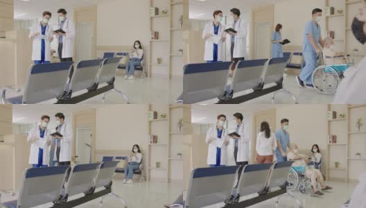 跟踪缓慢:两名医生在医院大堂或走廊与忙碌的护士、坐轮椅的老年患者、病人、带着医用口罩在接待处等候的亲属一起讨论和交谈。高清在线视频素材下载