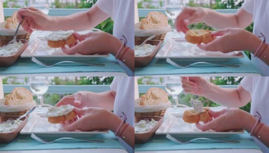 一名女子在海边的一家餐馆里吃着蘸着希腊酸奶黄瓜酱的面包。高清在线视频素材下载