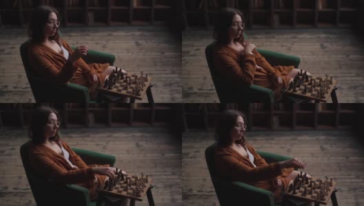 严肃睿智的女棋手戴着眼镜，坐在暗室里下棋走棋。高清在线视频素材下载