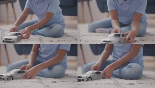 小男孩玩着心爱的玩具车，坐在地板上享受休闲时光的游戏高清在线视频素材下载