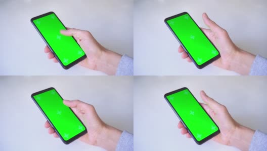 特写镜头。男子在绿色的chromakey屏幕上滚动，一只手拿着智能手机的拇指，放在白色的桌子上。概念技术，人，社交网络，网络冲浪。水平的视频高清在线视频素材下载