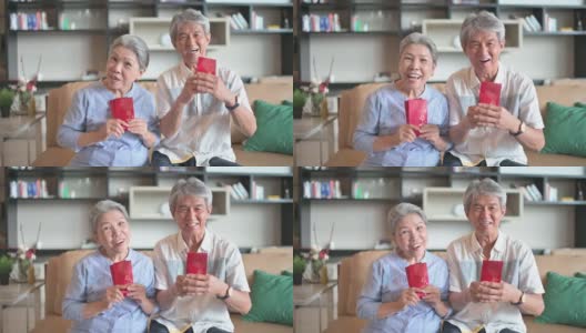过年的老两口爷爷奶奶在客厅拿着红包看镜头高清在线视频素材下载